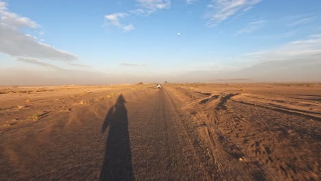 motorbikes driving along a sand covered road through the moroccan desert kicking up dust in their wake