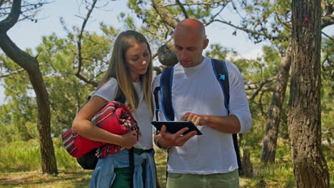 una pareja de mochileros usando una tableta al aire libre