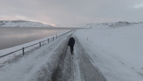 girl walking on slippery frozen road, westfjords