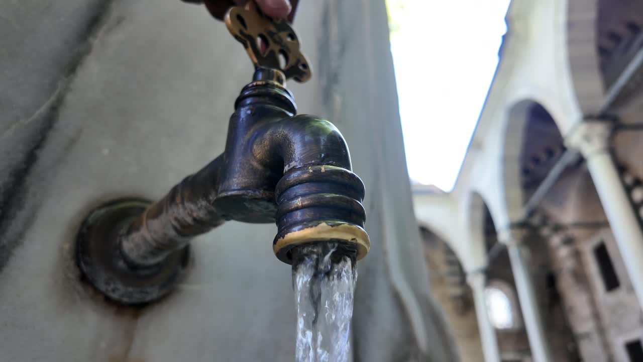 Antique Brass Faucet with Flowing Water at a Historic Site