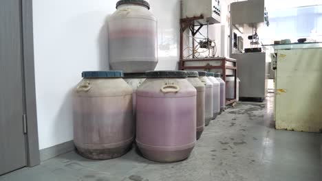 large barrels of chemicals lined up in a lense factory, showcasing industrial storage and materials used in production. factory setting. jiangsu province, china.