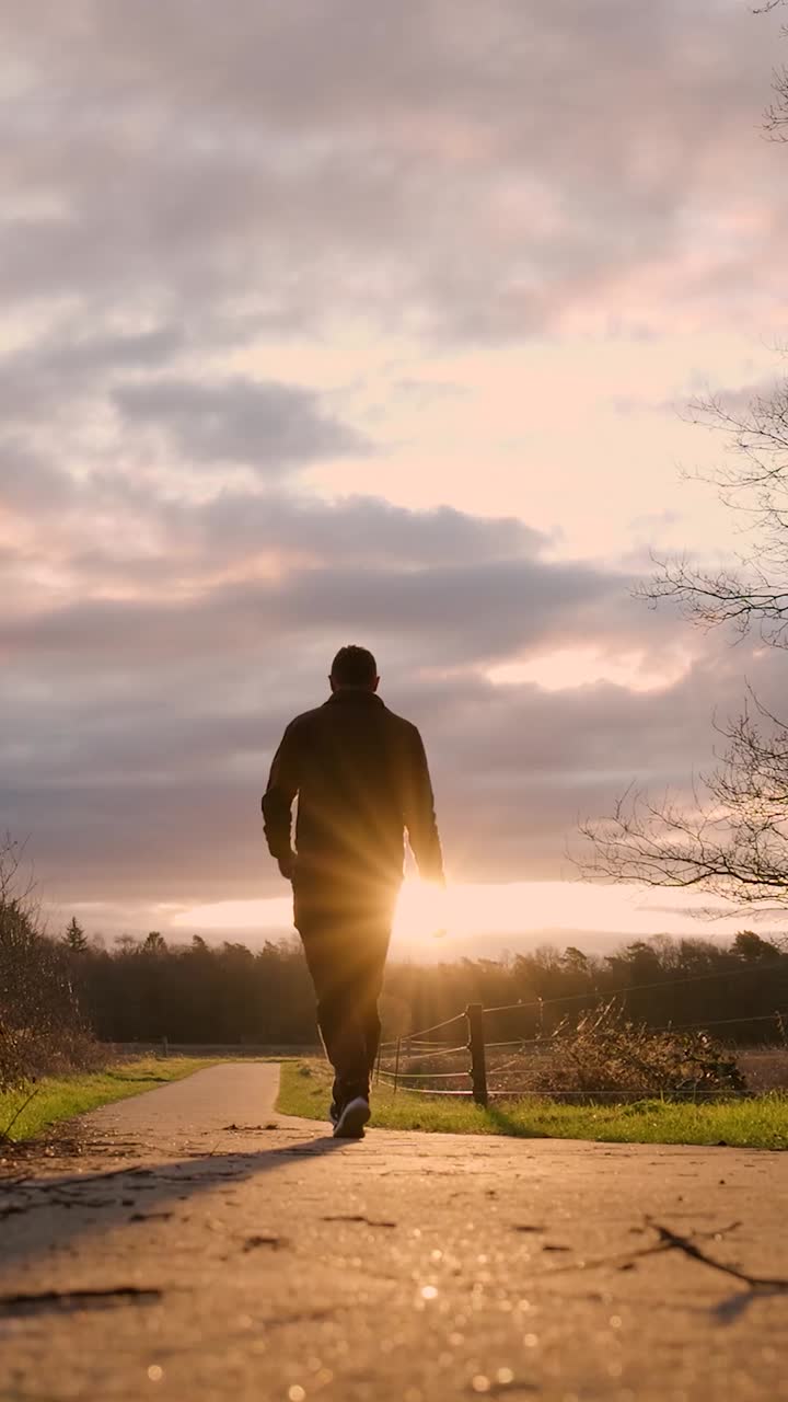 hombre caminando por un camino al atardecer