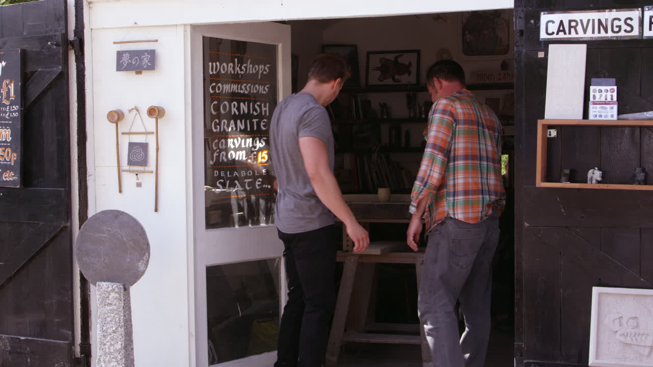 albañil con aprendiz fuera del taller filmado por la cámara roja