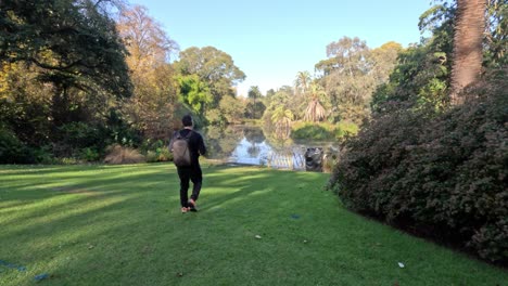 person walking towards a pond in gardens