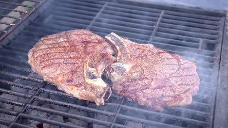 zoom out view of big juicy steaks cooking on hot charcoal