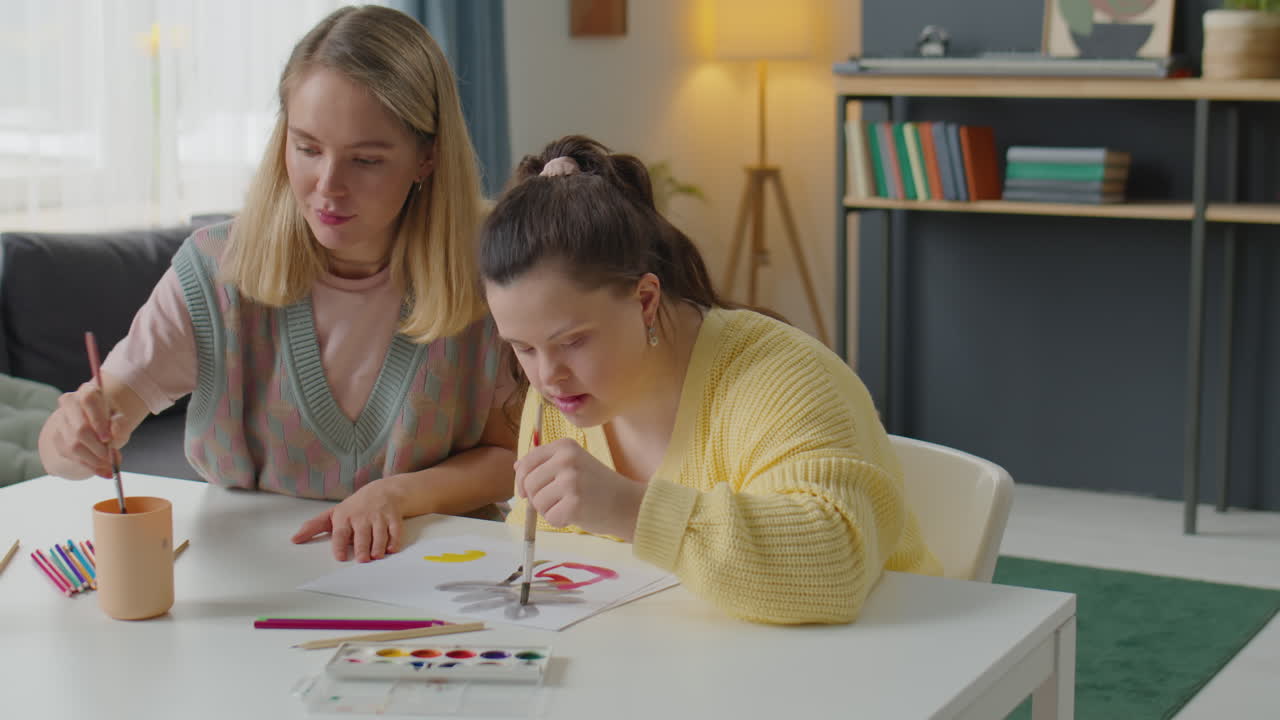 Donna e ragazza con sindrome di Down che dipingono un quadro insieme