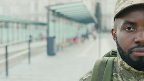 retrato de un alegre soldado sonriendo en la parada de autobús