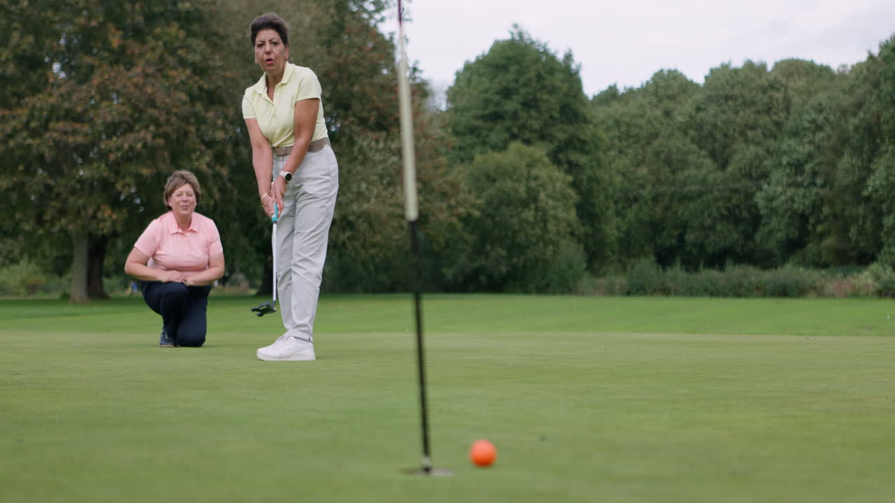 Women playing golf on a green course
