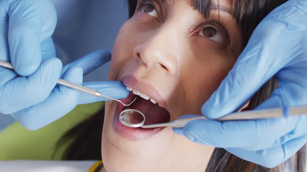 Manos de dentista masculino examinando los dientes de paciente femenina en una clínica dental moderna
