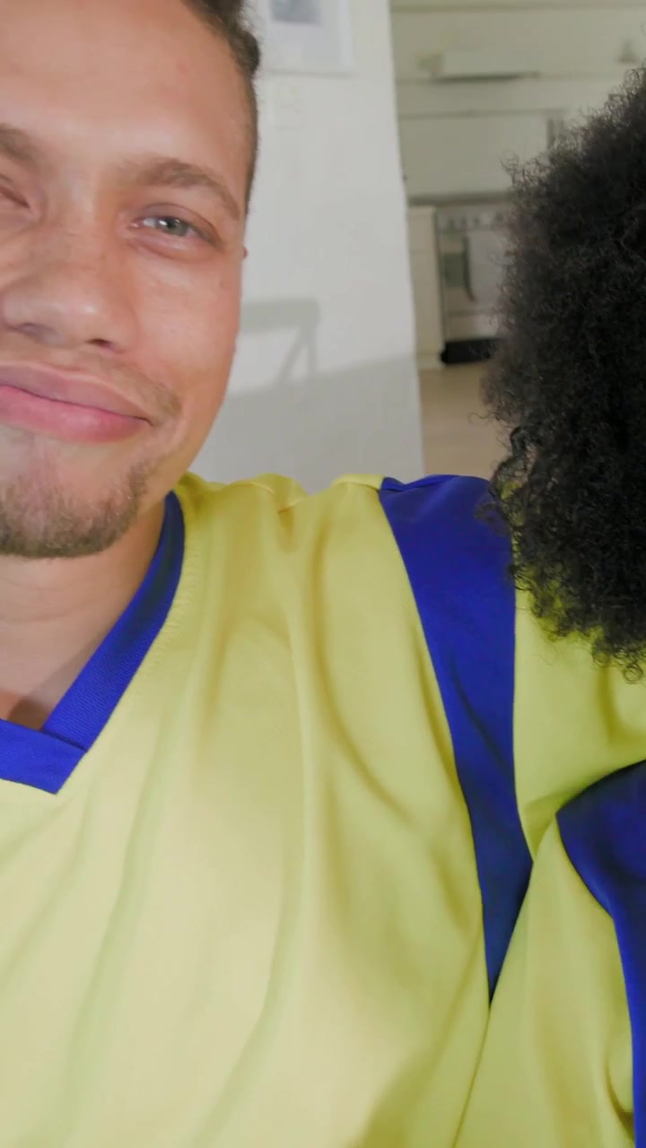Video verticale: Donna che filma, tiene il telefono per un selfie a casa, con un top giallo, unendosi a un uomo che la afferra scherzosamente e ride