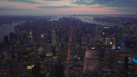 Vista-Aérea-Panorámica-De-La-Gran-Ciudad-Rodeada-De-Agua-En-El-Crepúsculo.-Edificios-De-Gran-Altura-Y-Tráfico-En-Avenidas.-Manhattan,-Ciudad-De-Nueva-York,-Estados-Unidos