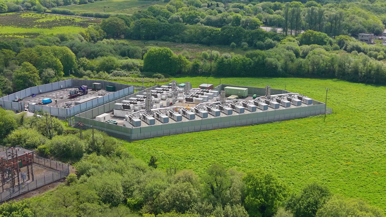 Approaching Aerial of modern gas peaking plant with exhaust stacks, generators, cooling systems. Facility provides rapid-response electricity to the grid during peak demand. Energy infrastructure. UK.
