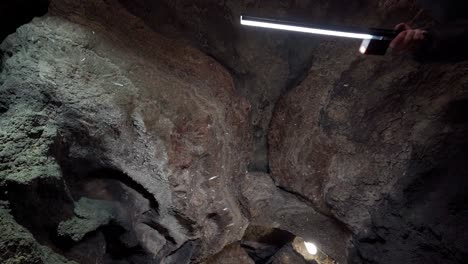 a speleologist illuminates and explores a dark stone cave a speleologist illuminates and explores a dark stone cave