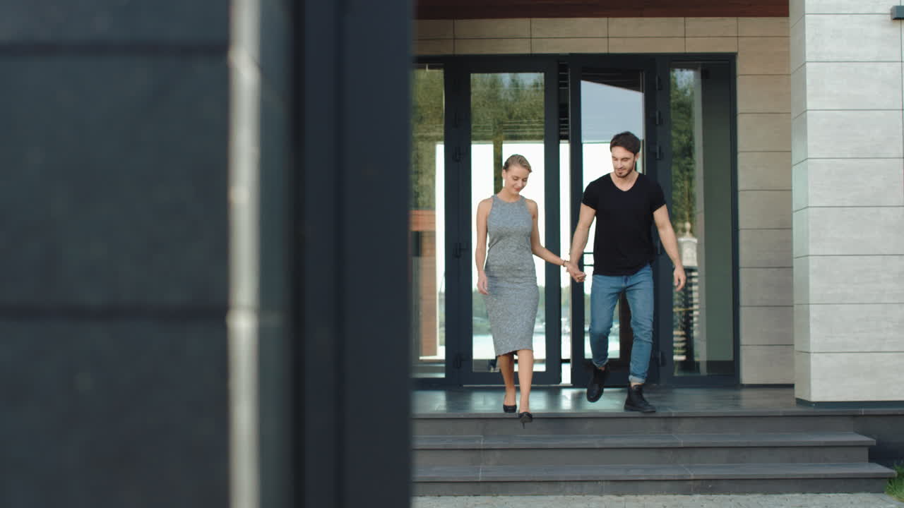 자신감 있는 커플이 하이테크 빌딩에서 함께 밖으로 나가고 있습니다.