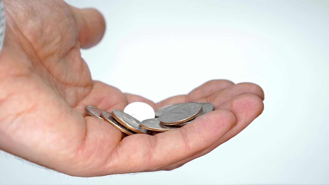 un hombre se toma su tiempo examinando una pequeña cosa en su mano, tratando de encontrar una moneda correcta