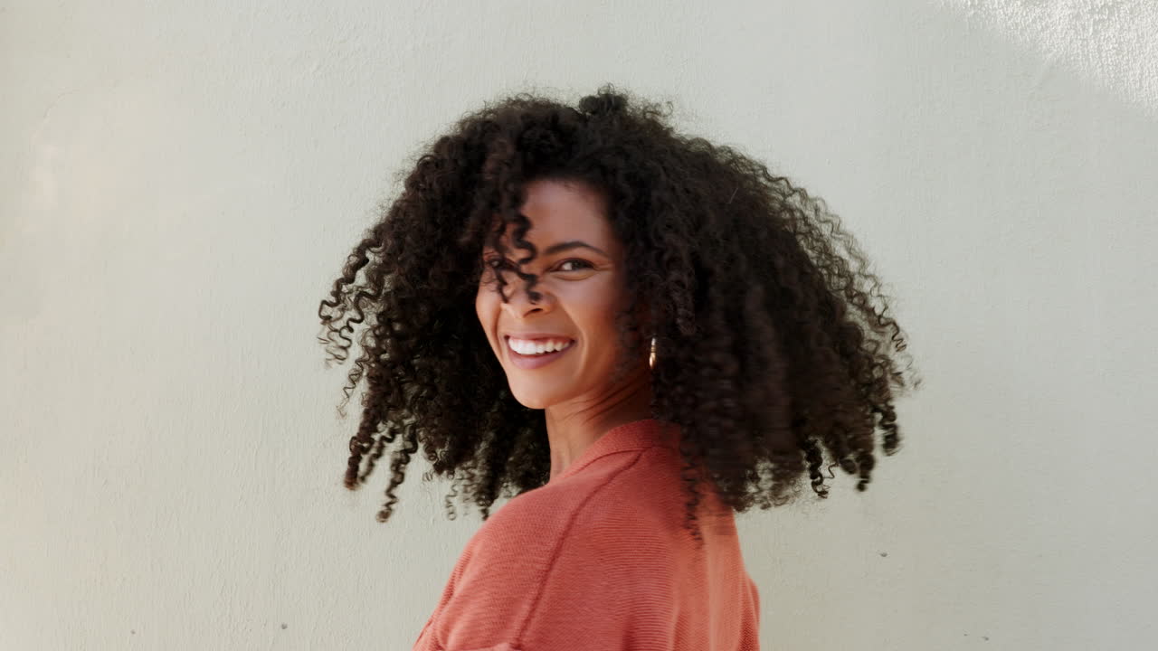 mujer afro sacudiendo rizos de cabello natural con blanco