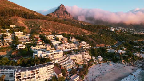 Puesta-De-Sol-De-Hoteles-En-La-Playa-De-Clifton-Con-Nubes-Rodando-Sobre-Cabeza-De-Leones-En-Ciudad-Del-Cabo,-Antena