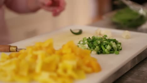 Close-Up-Of-Peppers,-Green-Onions,-Chili-Pepper-And-Garlic-On-Cutting-Board-In-Slow-Motion