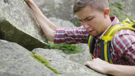 a heavy climb up the mountain through the rocks a young concentrated man scrambles up the stonesl 4k