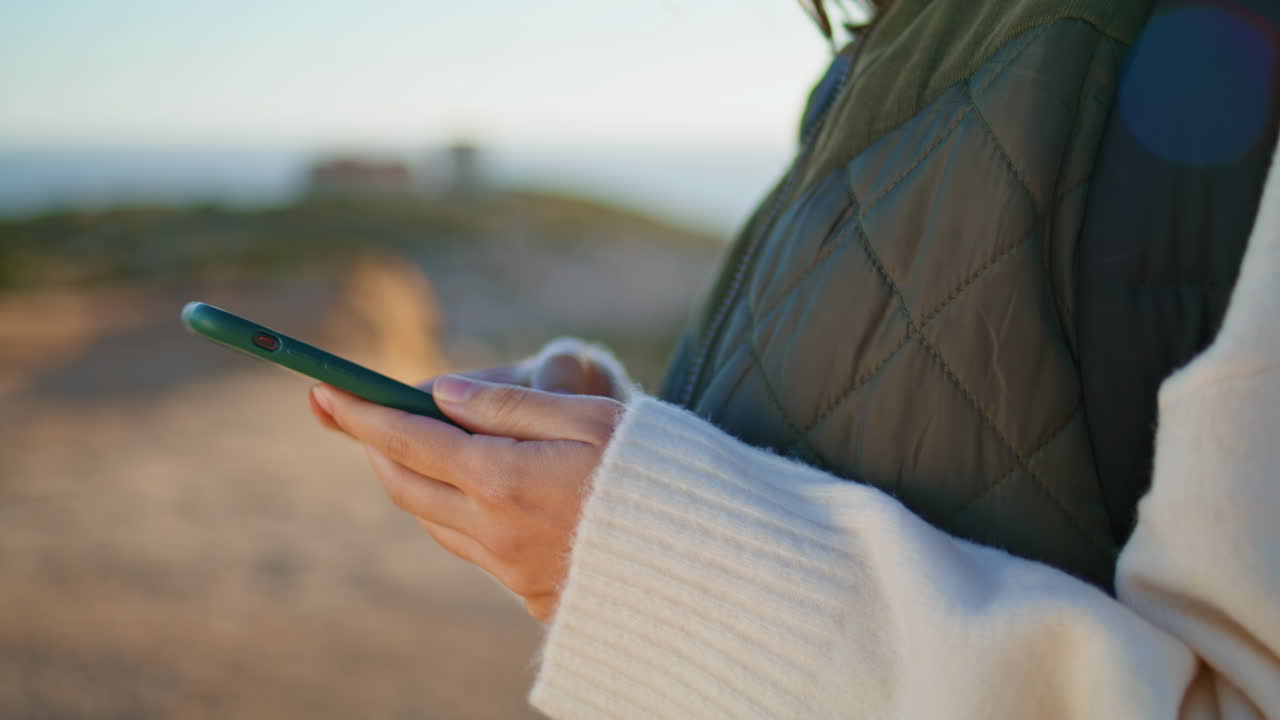 las manos del viajero enviando mensajes de texto por teléfono en la montaña del mar. niña desconocida usando teléfono inteligente