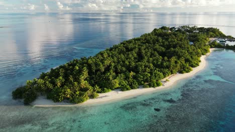 aerial drone video slowly flying around the local island of thinadhoo at sunrise in the maldives