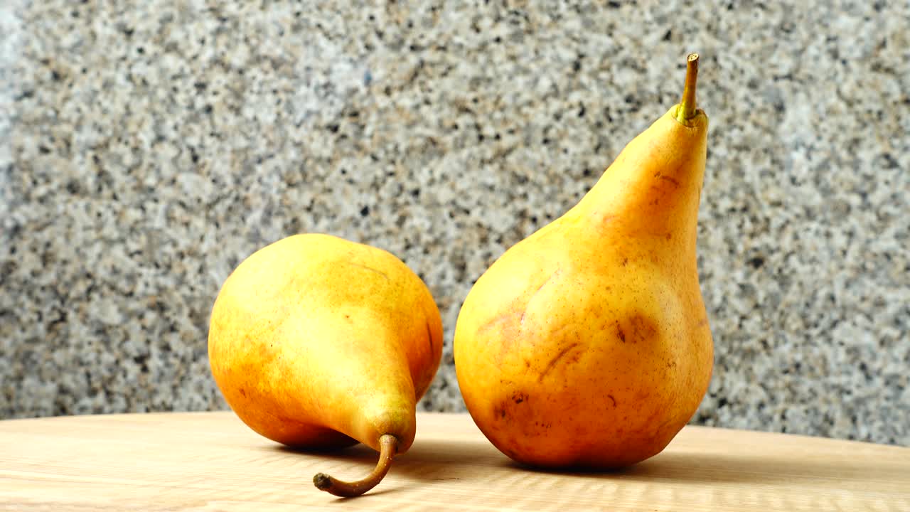 Pere su un tagliere di legno in cucina. Ripresa in movimento