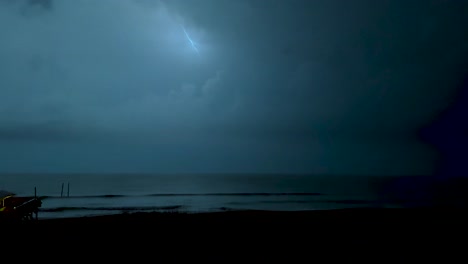 thunder and lightning during a spring storm on the beach with a pier in the foreground