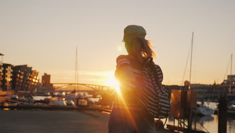 mujer activa se regocija al amanecer sobre el puerto deportivo corre hacia adelante levanta las manos al amanecer en bergen