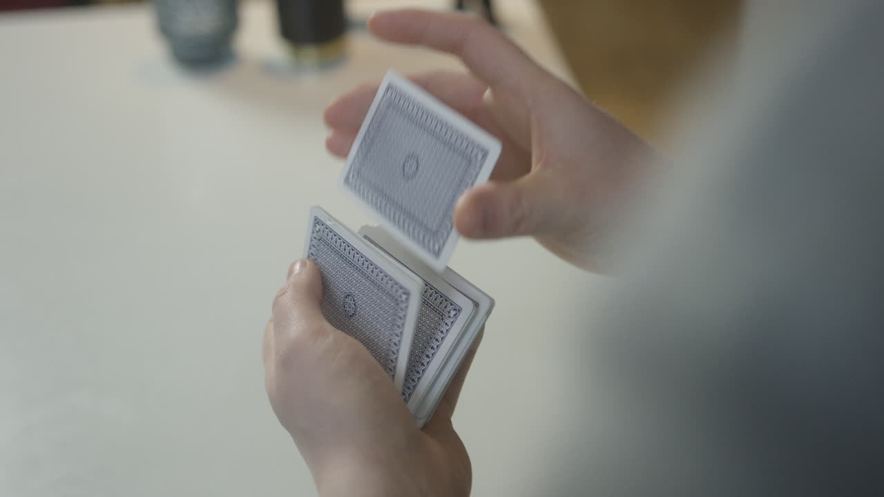 manos masculinas barajando una baraja de cartas detrás de un ambiente informal
