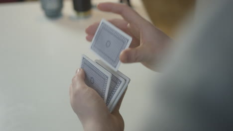 Male-hands-shuffling-a-deck-of-playing-cards-behind-view-casual-setting