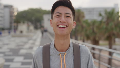초상화 행복한 젊은 아시아 남성 관광객 웃음 여름 휴가를 즐기고 독립적인 십대 남성이 해가 지는 도시 해안가에서 즐겁게 보입니다.