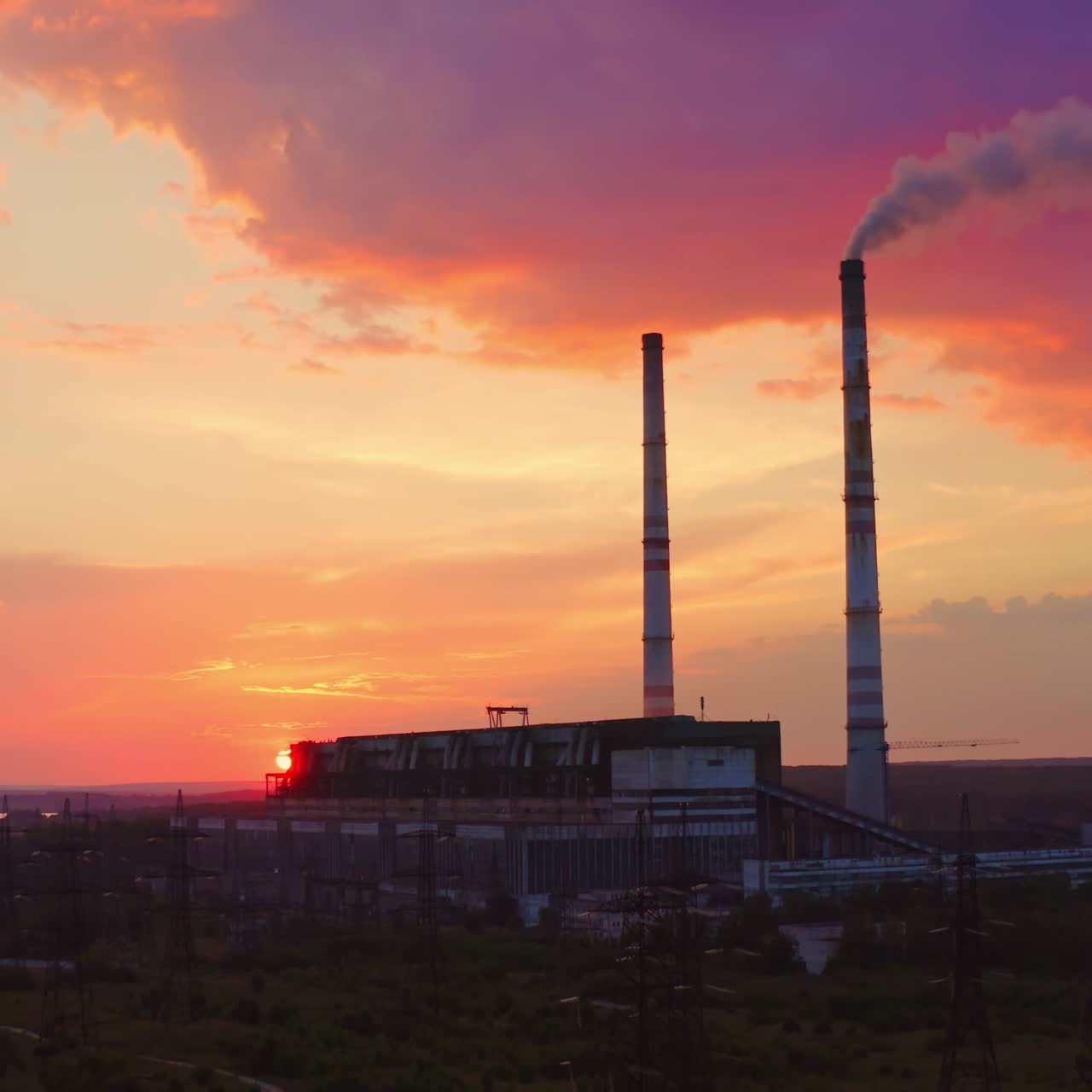 Harmful industry causes ecological problems. Dangerous smoke goes from chimney of manufacturing on the colorful sky background.