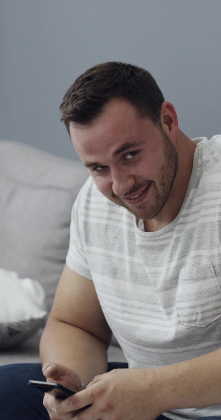 Uomo che sorride allo smartphone interrotto da una donna in piedi lì vicino