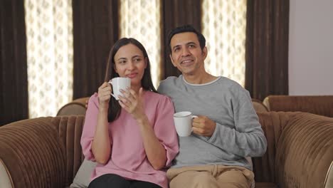 una feliz pareja india bebiendo té y planeando algo