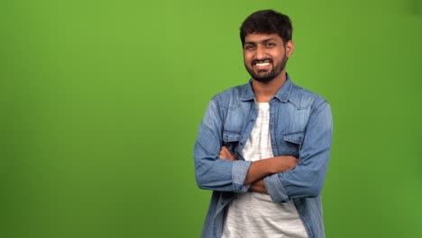 asian bearded man with toothy grin standing tall in front of green screen and greeting