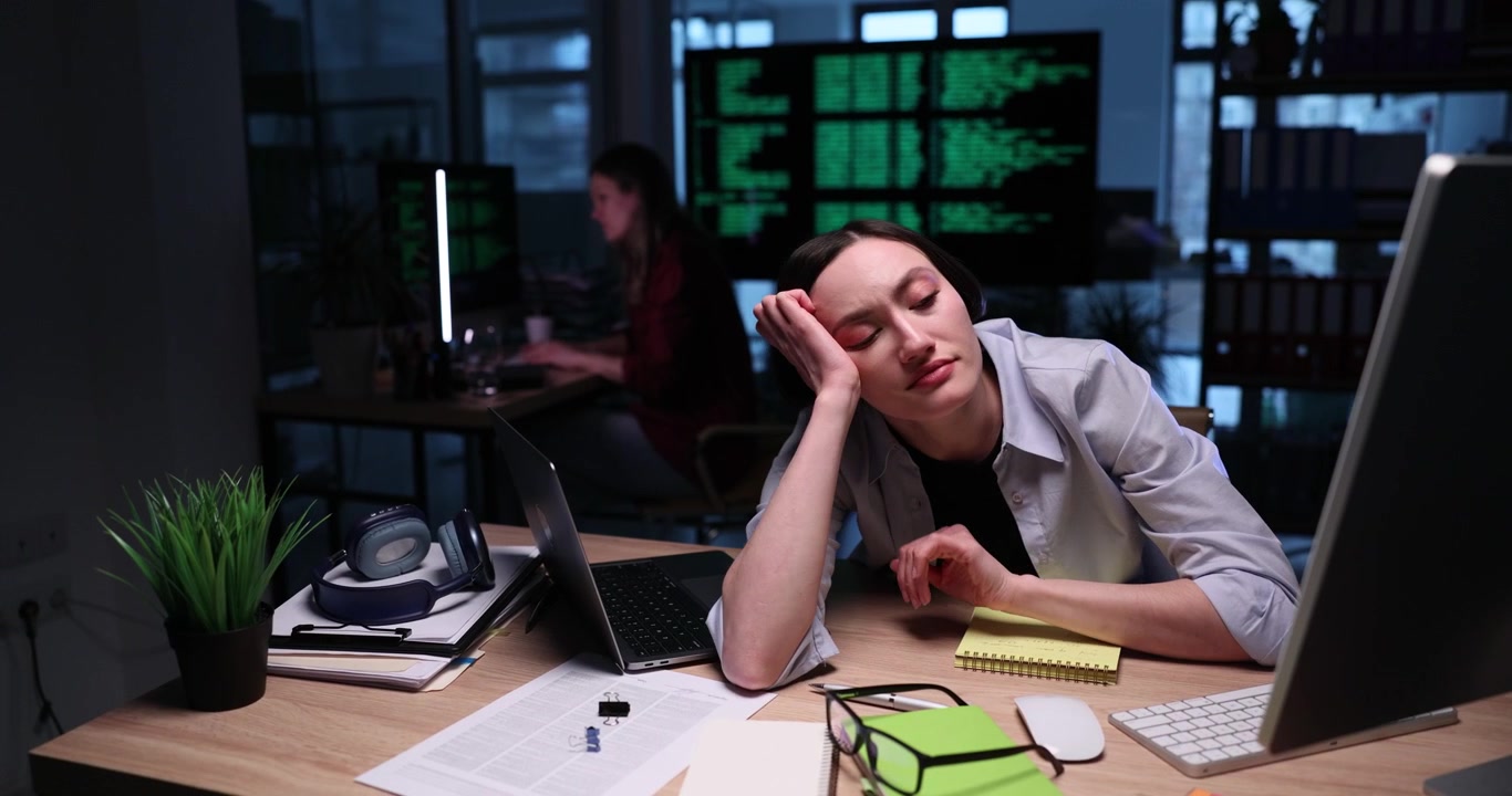 Sleepy businesswoman yawns working on modern laptop late at night