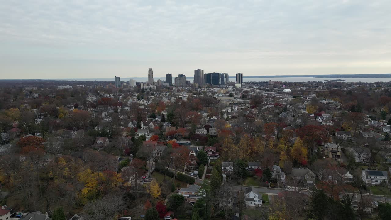 Aerial view of Pelham NY, showcasing tree-lined streets and residential homes during autumn. Overcast skies and fall colors create a scenic suburban neighborhood vibe