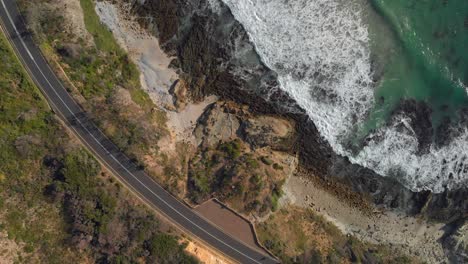 static-aerial-view-of-car-driving-on-coastal-road-by-the-sea