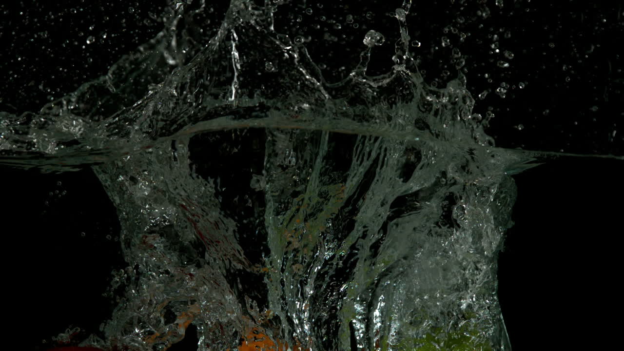 사과 오렌지와 라임이 검은 바탕에 물에 잠기고