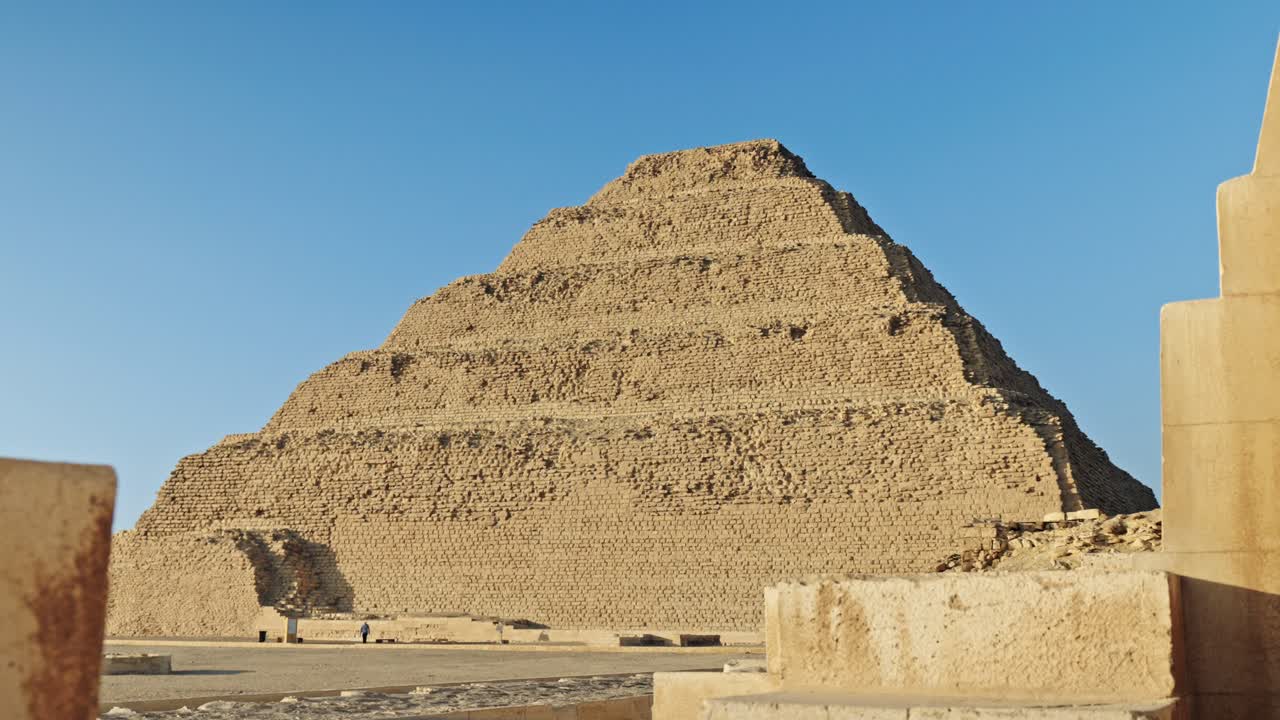the Step Pyramid of Djoser in the Saqqara necropolis, Egypt, bathed in the warm, golden light of the setting sun