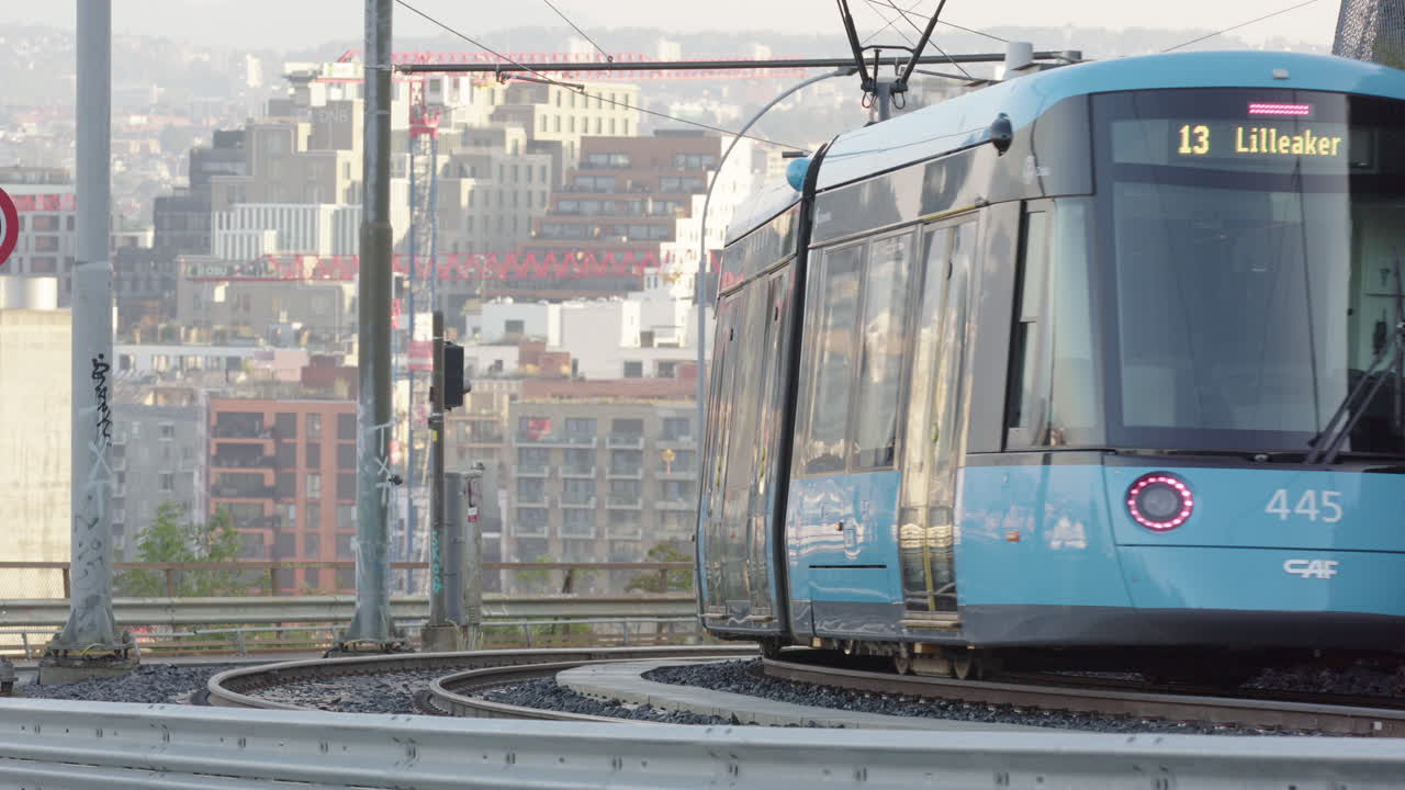 A modern tram descends Kongsveien in front of Bjorvika, central Oslo
