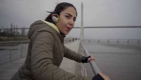 Mujer-Hindú-Concentrada-Con-Auriculares-Haciendo-Flexiones-Desde-Una-Barandilla-De-Metal