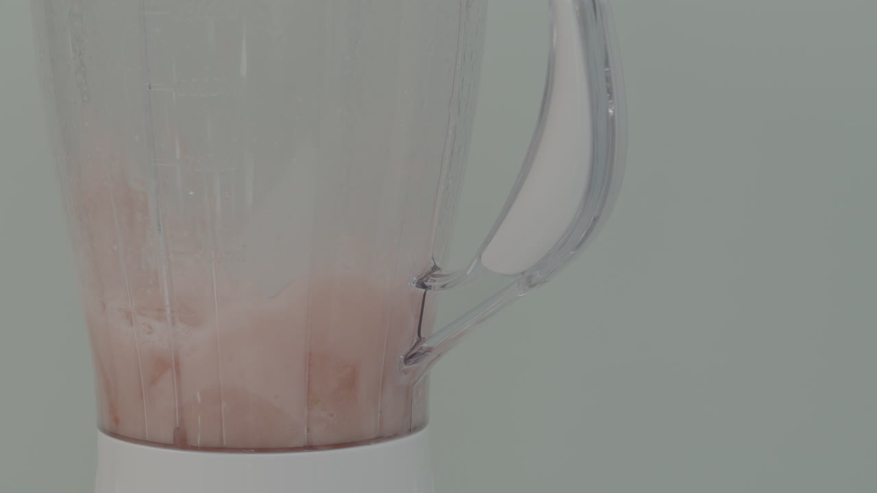 foto de cerca de una licuadora blanca mezclando fresas y hielo juntos en cámara lenta para hacer un batido o batido de leche