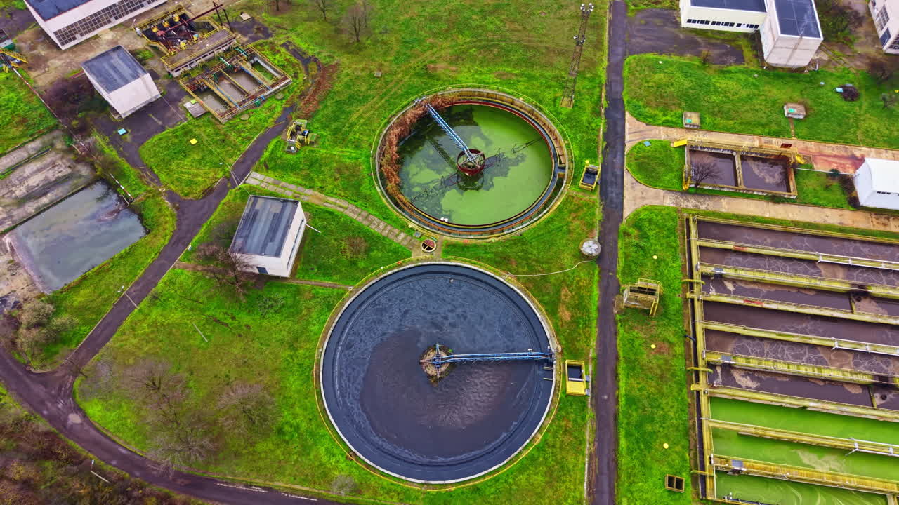 View of a wastewater treatment plant showing circular and rectangular tanks for water processing during daytime