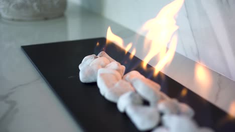 close up tracking shot of indoor gas fire place with white pebbles