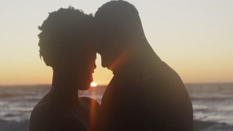 Video-of-happy-african-american-couple-embracing-on-beach-at-sunset