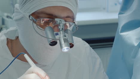 surgeon man with optical equipment in clinic. focused doctor cardiologist with laser scalpel conducts coronary artery bypass surgery in hospital