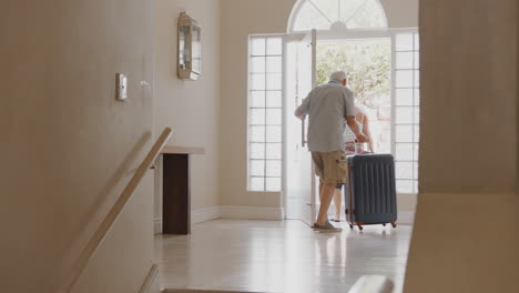 senior couple with suitcase opening front door and leaving for vacation