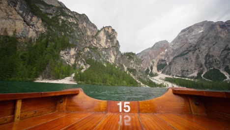 wooden boat drifting across lake braies in the prags dolomites, south tyrol, italy - pov