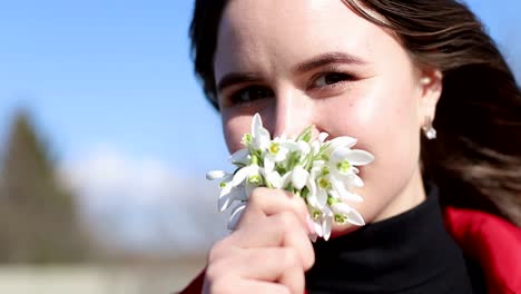 beautiful smiling brunette girl holding bouquet of snowdrops first spring flowers beautiful smiling brunette girl holding bouquet of snowdrops first spring flowers girl holding flowers and smiling to camera spring flowers